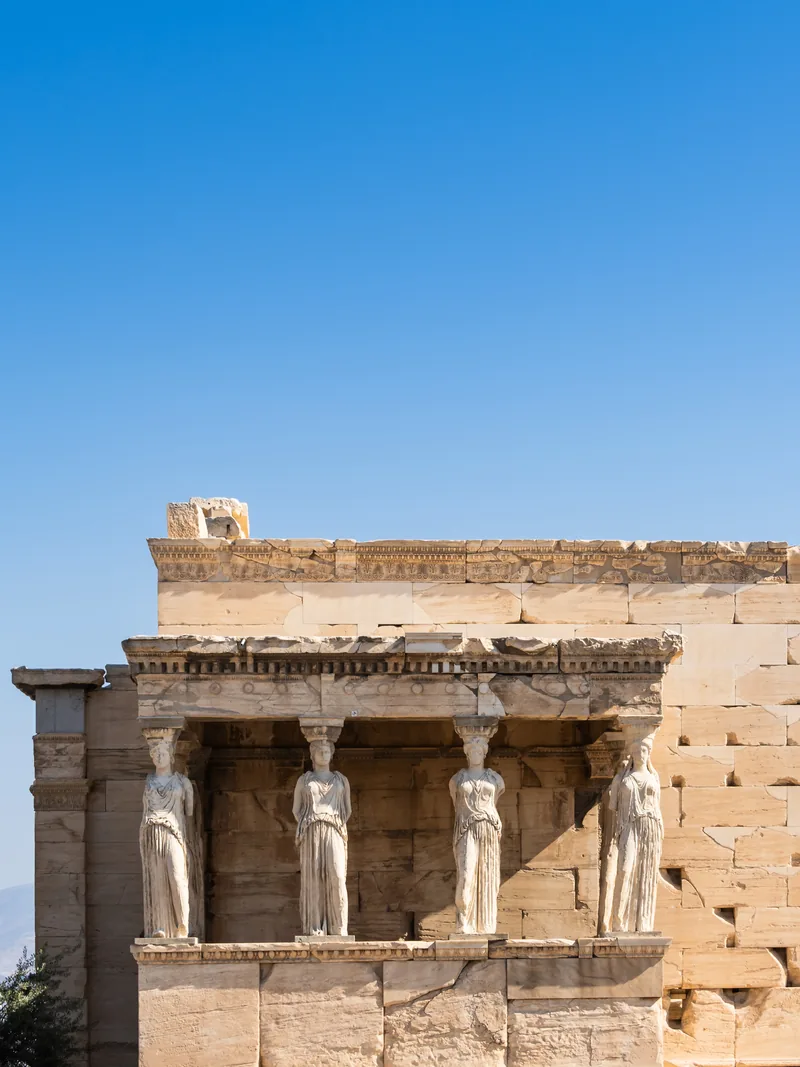 The Caryatids, carved maidens holding up the porch of the Erechtheion, against a deep blue sky.