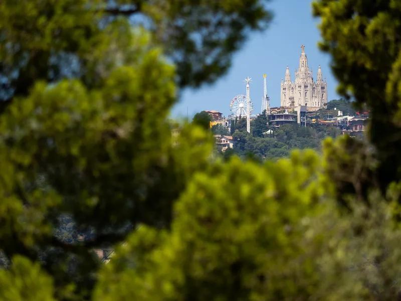 The Tibidabo church and amusement park on a distant hilltop, framed by green trees.