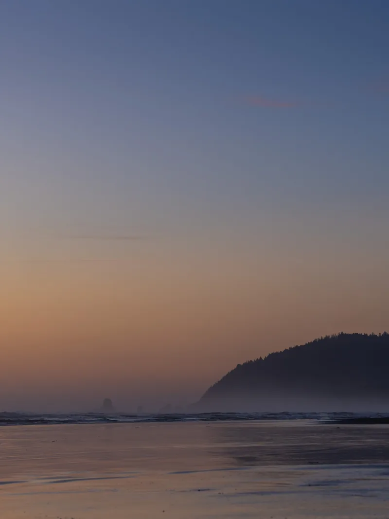 A headland fading into haze under a soft evening sky.
