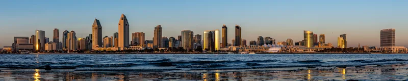A panorama of the San Diego skyline glowing across the bay at sunset.