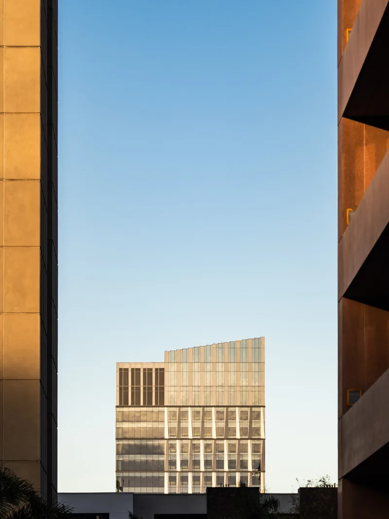 A modern glass building framed between two sunlit walls.