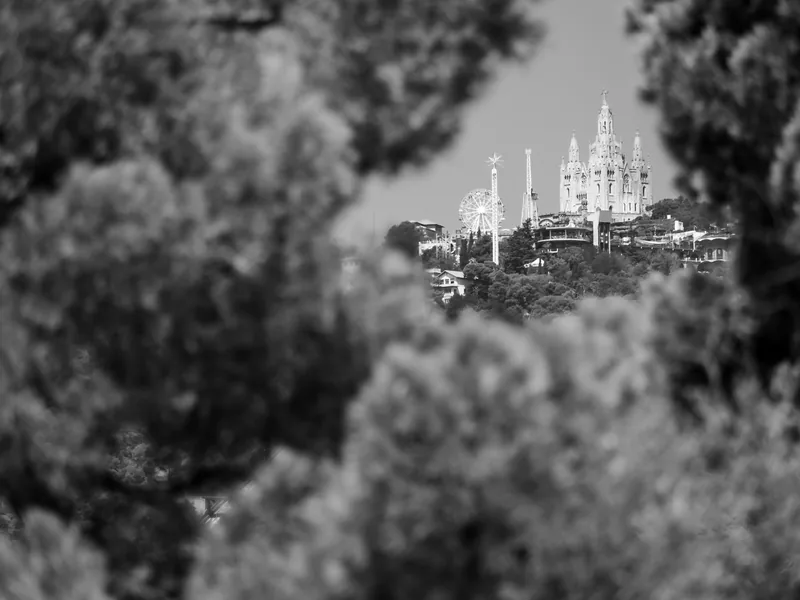 The Tibidabo church on its hilltop framed by blurred pine trees, in black and white.