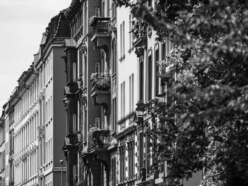 Ornate Frankfurt apartment façades along a tree-lined street, in black and white.