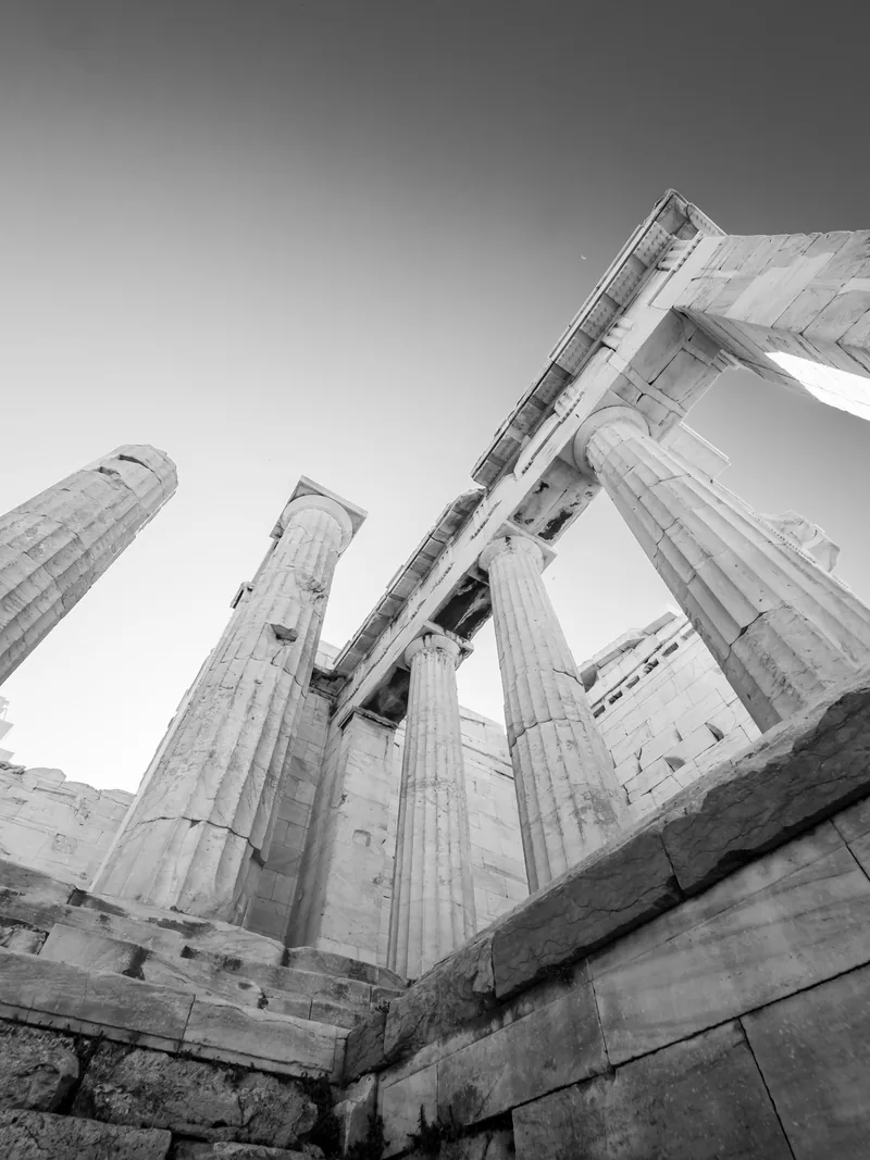 Columns of the Propylaea seen from below against the sky, in black and white.