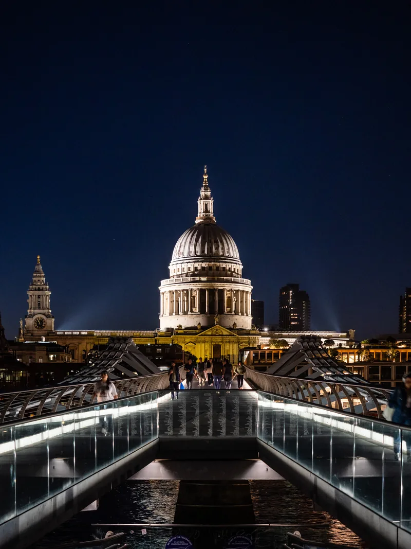 St Paul's Cathedral lit up at night at the end of the Millennium Bridge.