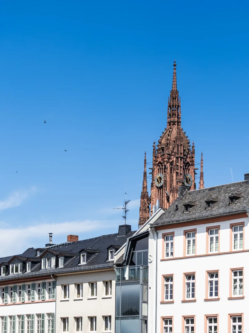The red sandstone tower of Frankfurt Cathedral rising above white townhouses.