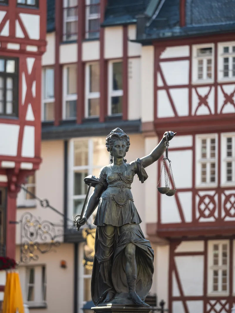 The bronze Justitia statue with her scales in front of red half-timbered houses on the Römerberg.