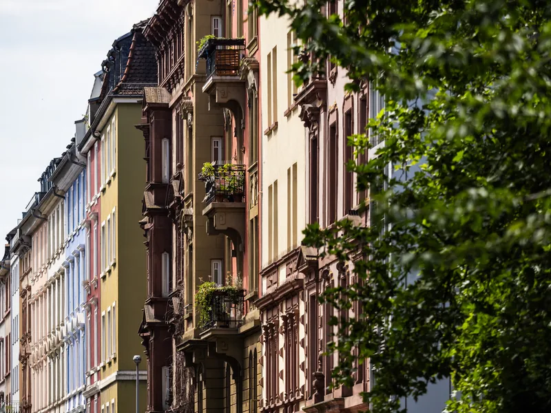 Colourful ornate apartment façades with balconies along a leafy street.