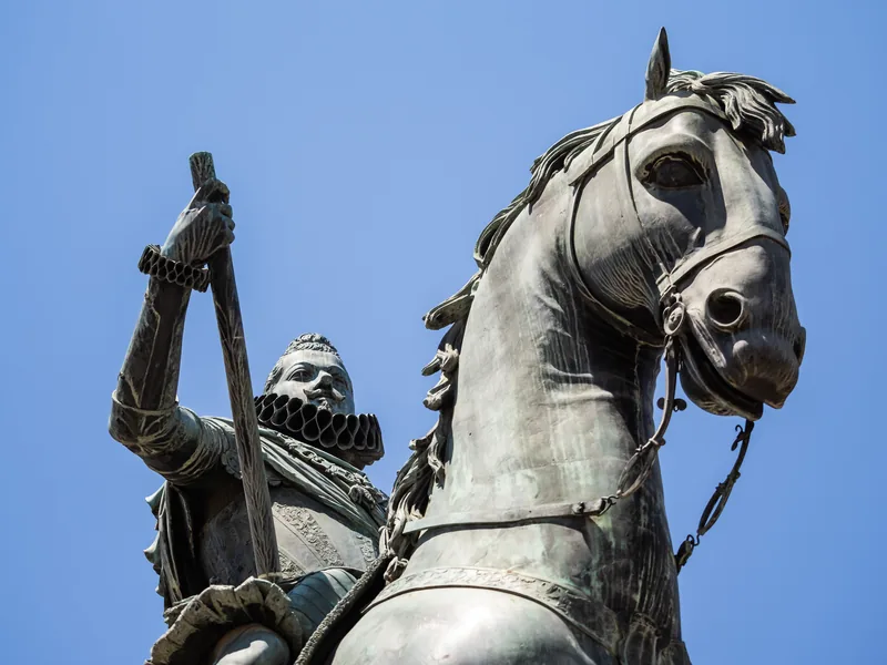 The bronze equestrian statue of Philip III against a clear blue sky.