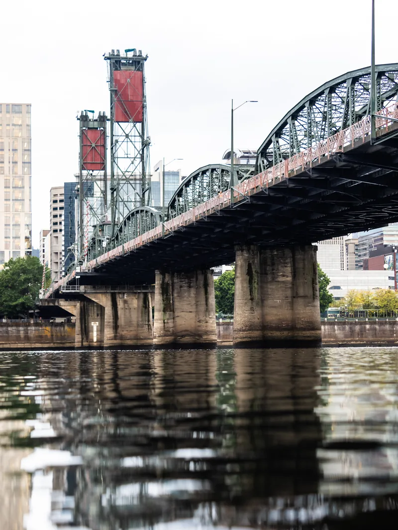 The Hawthorne Bridge and its red lift towers reflected in the Willamette River.