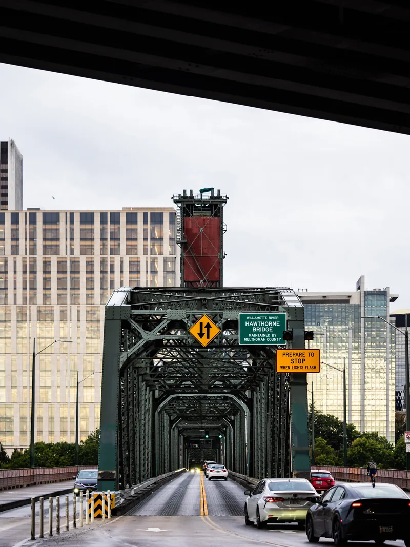 Traffic crossing the green steel truss of the Hawthorne Bridge toward downtown.