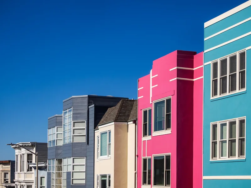 Brightly painted pink, blue and teal houses against a deep blue sky.