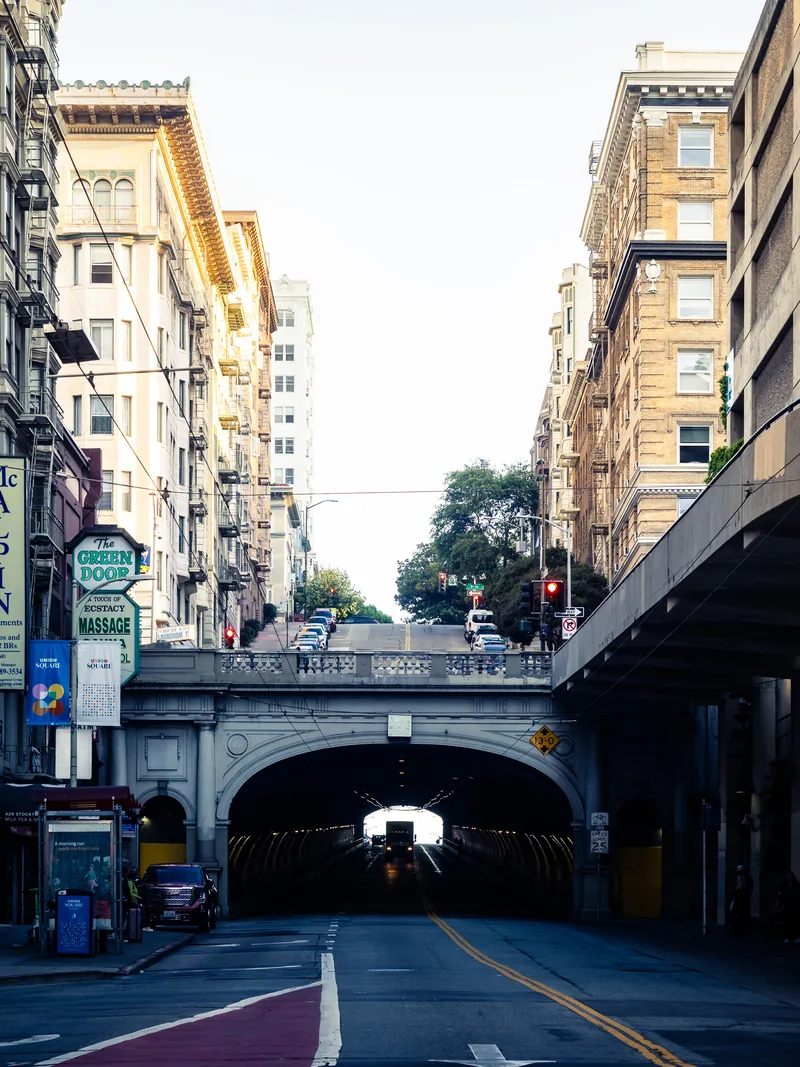 Traffic lanes leading into a city tunnel between tall buildings.