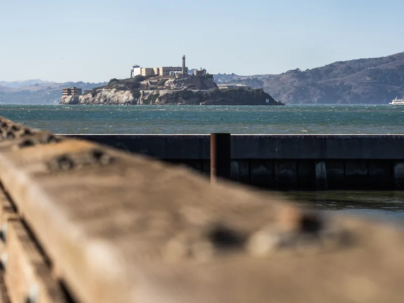 Alcatraz Island across the bay beyond a weathered pier railing.