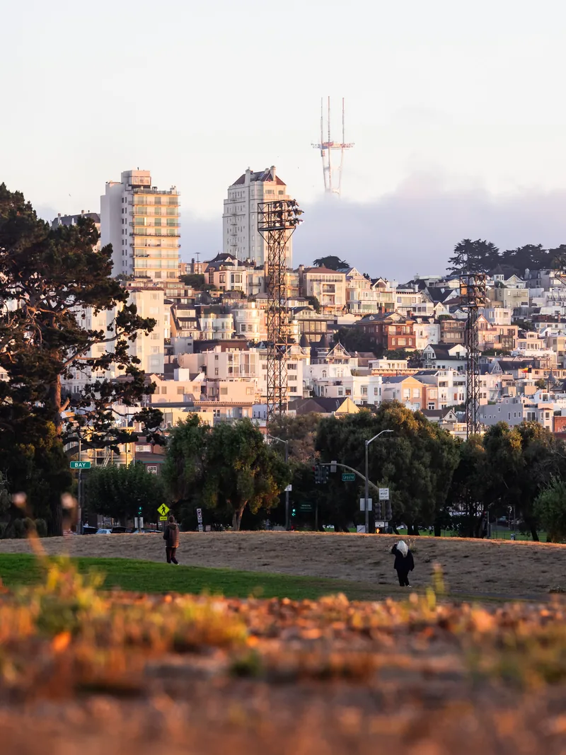 Telegraph Hill and Coit Tower above rows of houses in soft evening light.