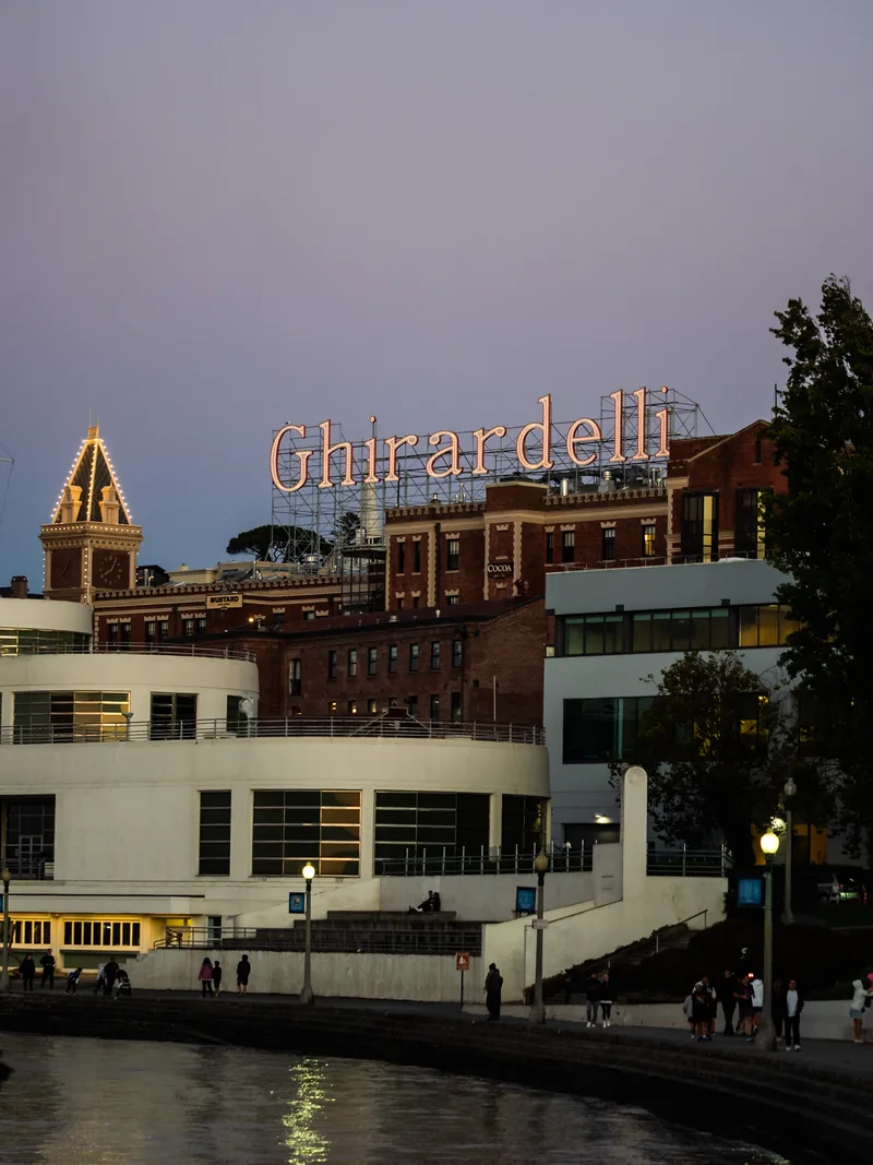 The Ghirardelli Square sign glowing at dusk above Aquatic Park.