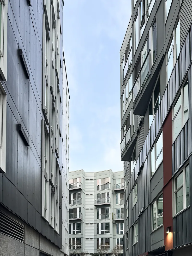 A narrow gap between modern apartment buildings under a blue sky.
