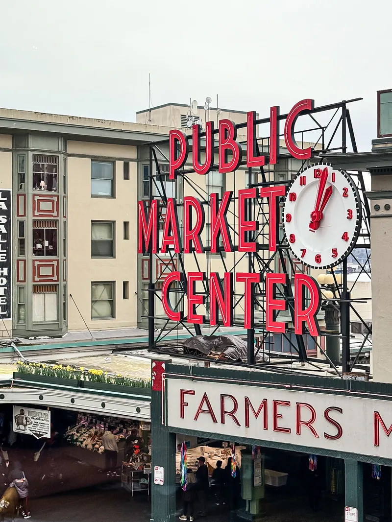 The red neon Public Market Center sign and clock above the Farmers Market entrance.