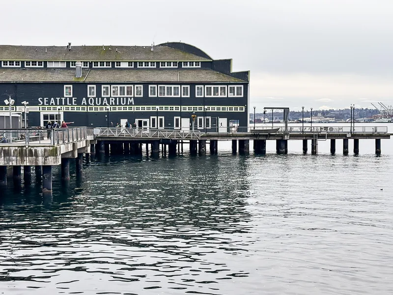 The Seattle Aquarium building on its pier over gray water.