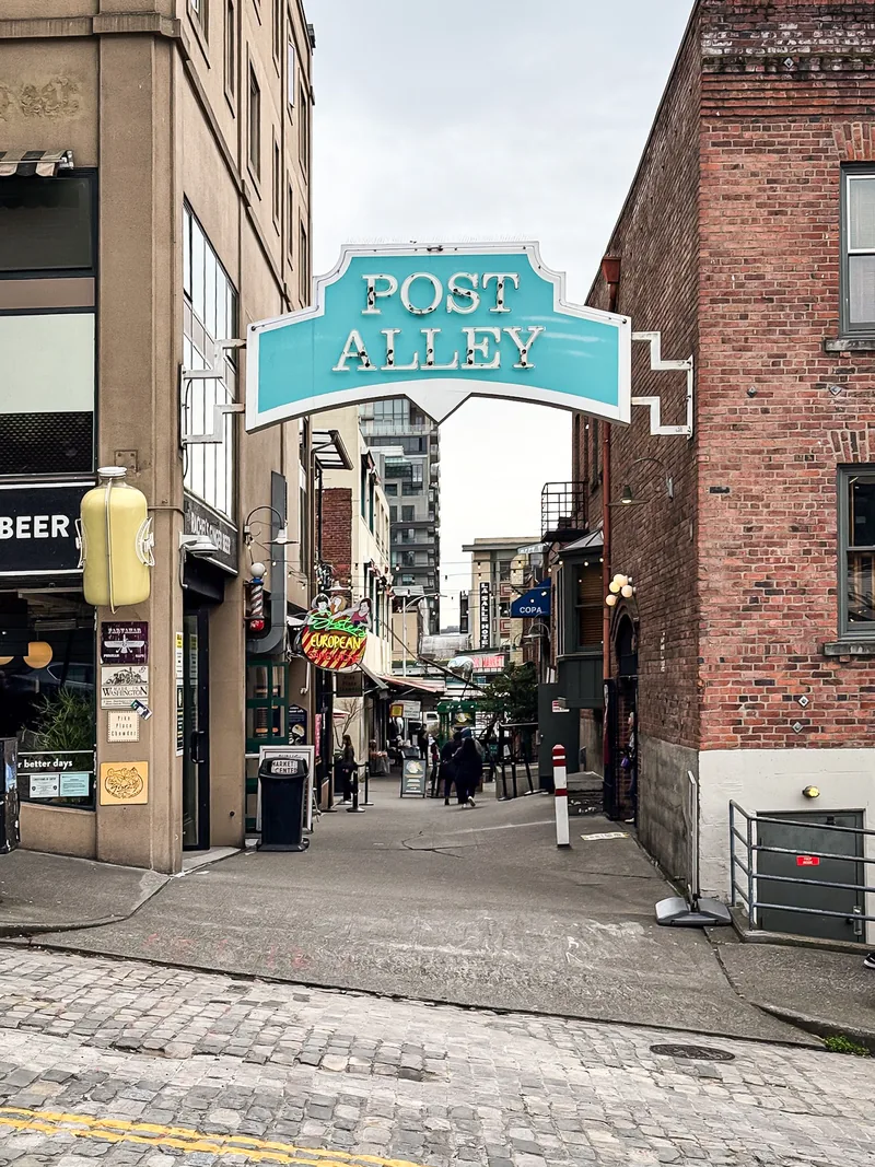 The teal Post Alley sign over a narrow brick alley.